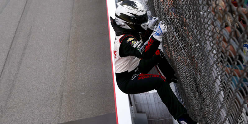 AJ Allmendinger climbs the fence