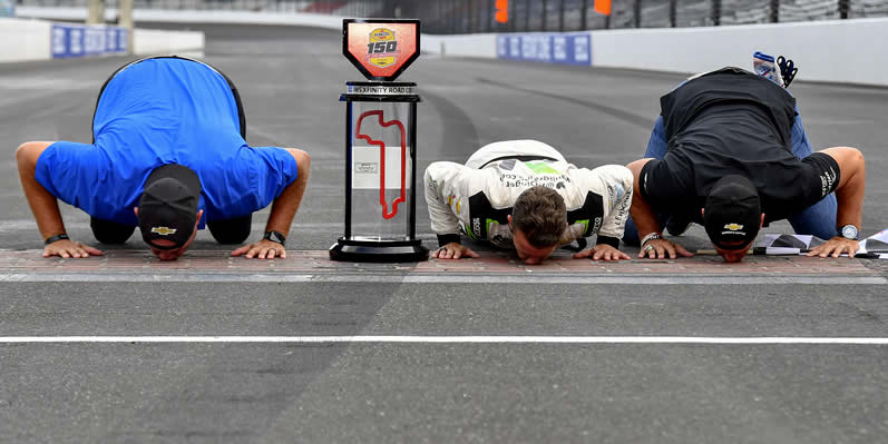 AJ Allmendinger, Matt Kaulig, and Chris Rice celebrate by kissing the yard of bricks