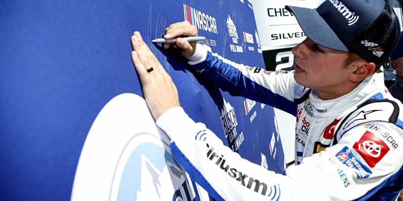 Christopher Bell signs the Busch Light Pole Award backdrop