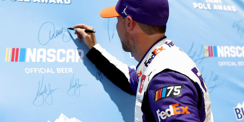 Denny Hamlin signs the Busch Light Pole Award backdrop